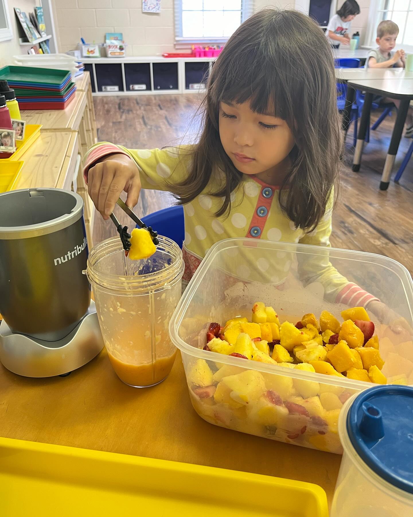 Preschool girl preparing fresh fruit smoothie all by herself