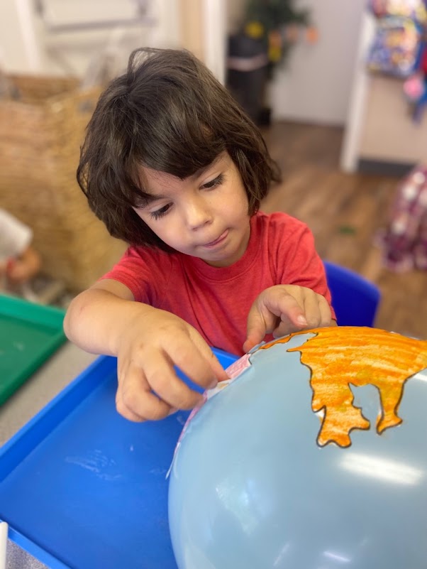 Preschool boy creating a model of the earth using art and a balloon