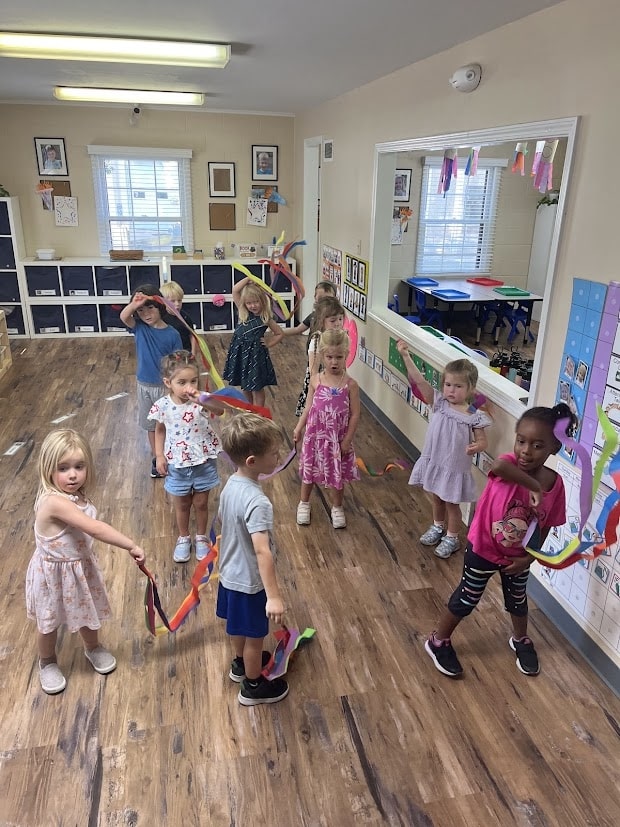 Preschool students dancing to music with ribbon wands