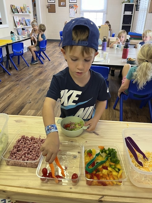 Student serving themselves a balanced meal with a variety of fresh foods for a snack