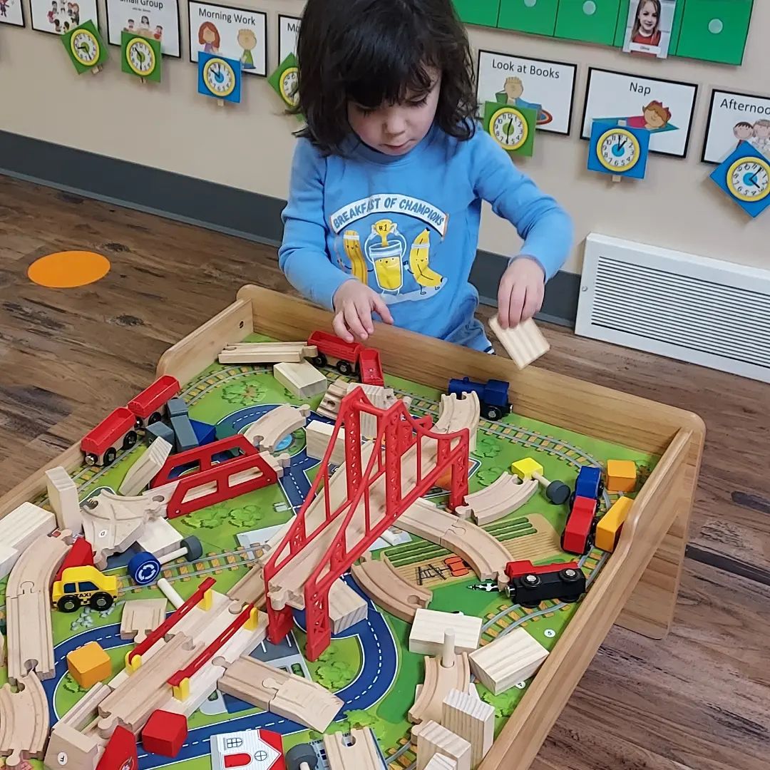 Preschool child working on STEAM building a train track with bridges