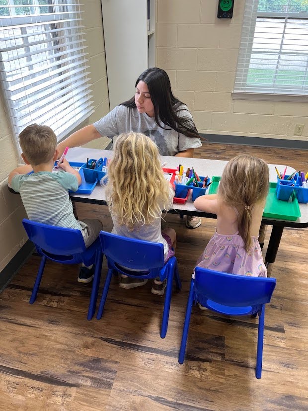 Students working with teacher in small group learning writing skills for elementary school readiness